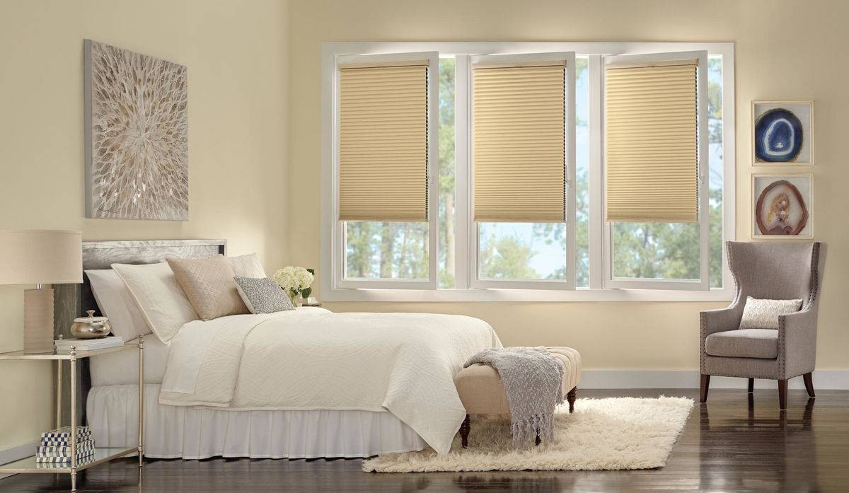 Comfortable bedroom with three windows outfitted with Hunter Douglas Duette® Cellular Shades near Mishawaka, IN