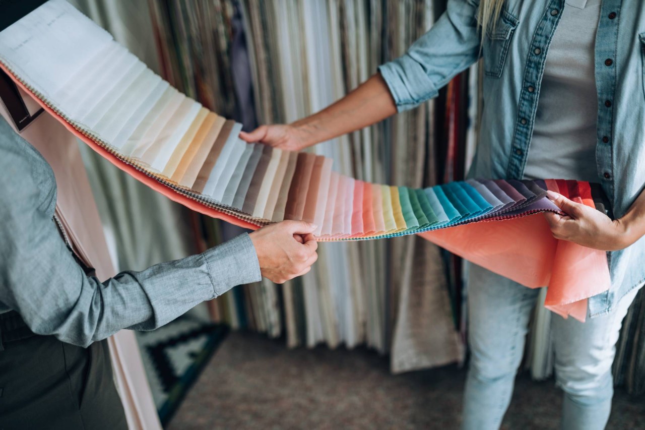A designer and client reviewing fabric swatches in various colors for their custom drapes at Midwest Blind & Shade near Mishawaka, IN