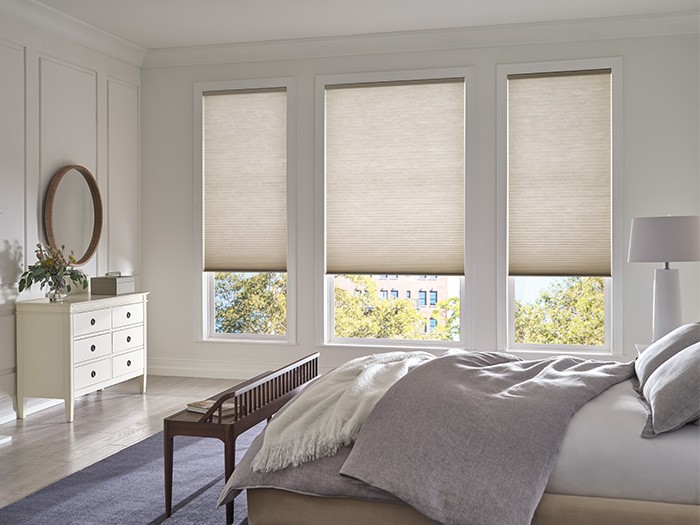Bright bedroom with tall windows featuring Duette® Honeycomb Shades.